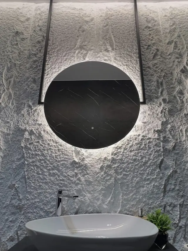Salle de bain avec mur en relief et miroir rond rétroéclairé